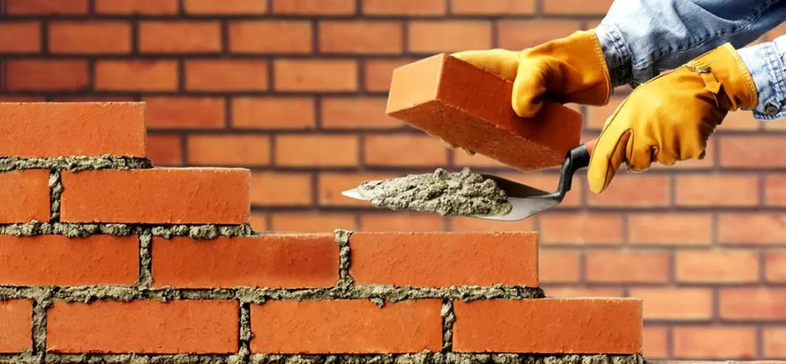 Imagen de albañil levantando una pared de tochos